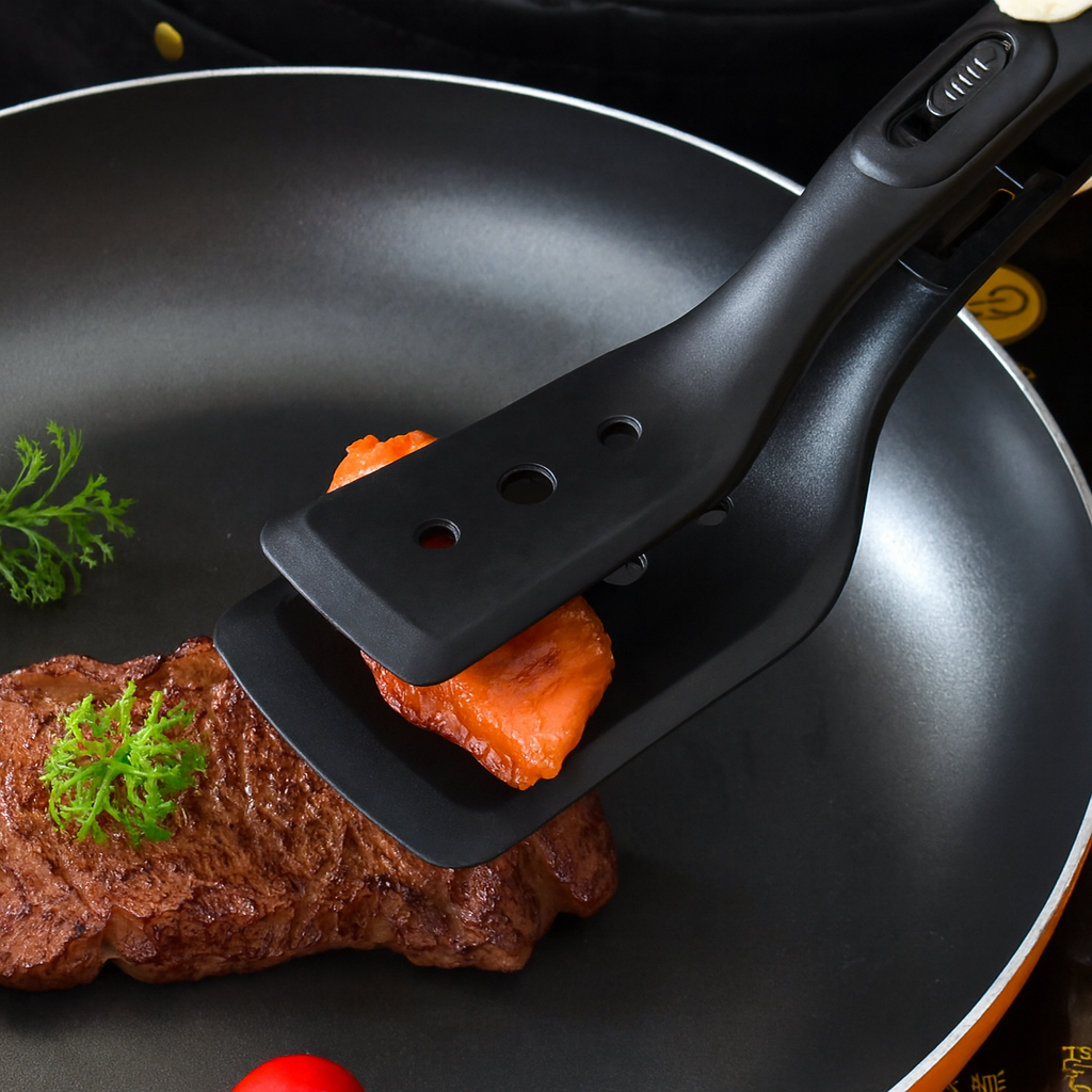 Nizo 2-in-1 mentelė sugriebusi lašišos gabalėlį virš kepsnio keptuvėje